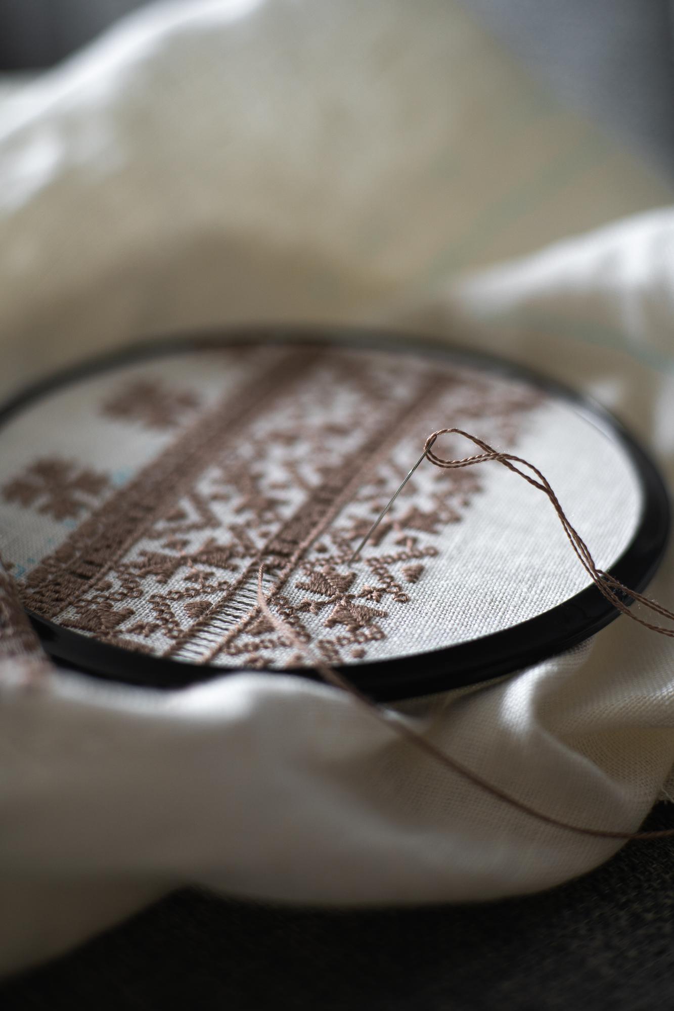 Rankų siuvinėjimo detalė ant lininio audinio